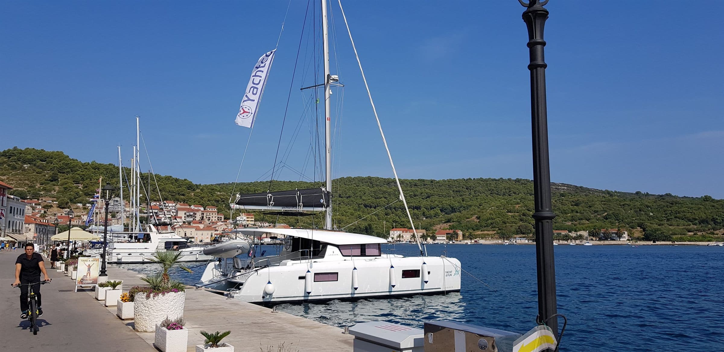 A catamaran flying the Yachtco flag moored on the quay at Vis