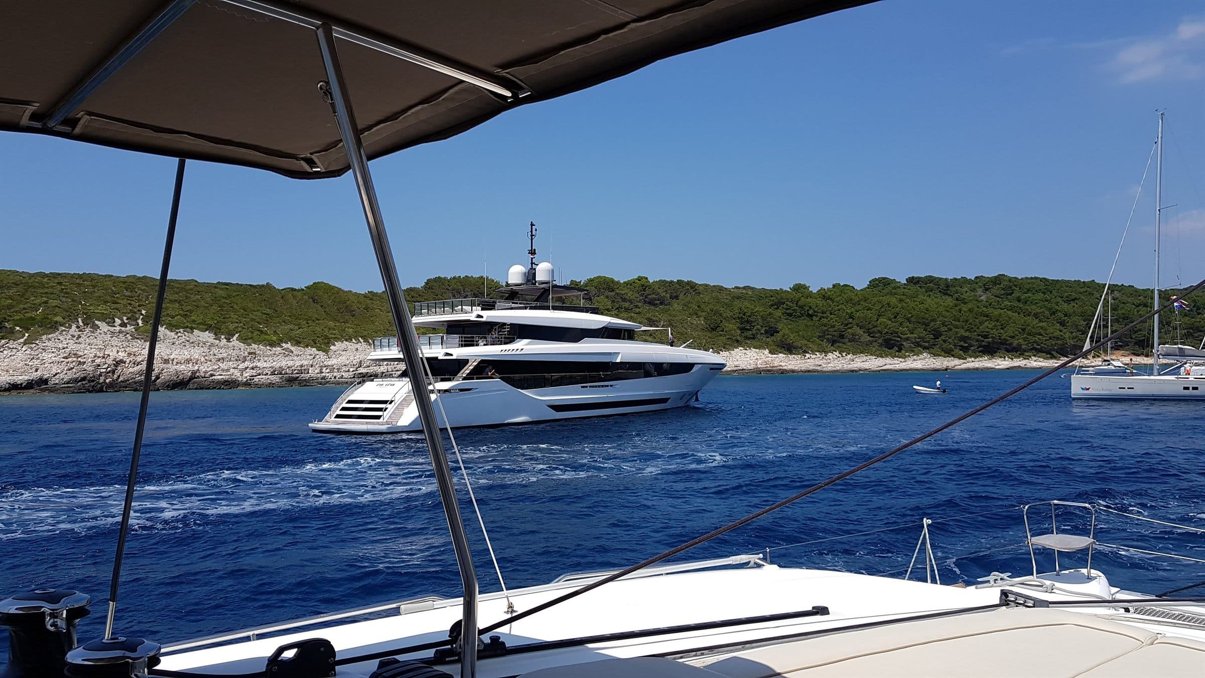 A crewed motor yacht passing the Pakleni islands, seen from a catamaran