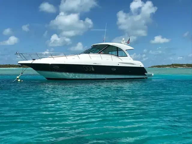 A sport cruiser lying to a buoy in shallow turquoise water