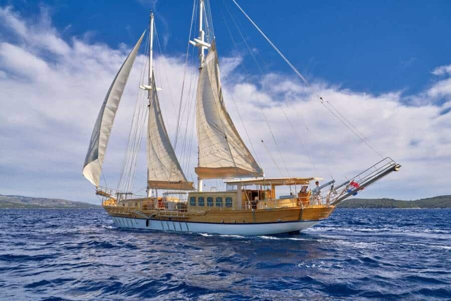 A wooden motorsailer under full sail off a Croatian island